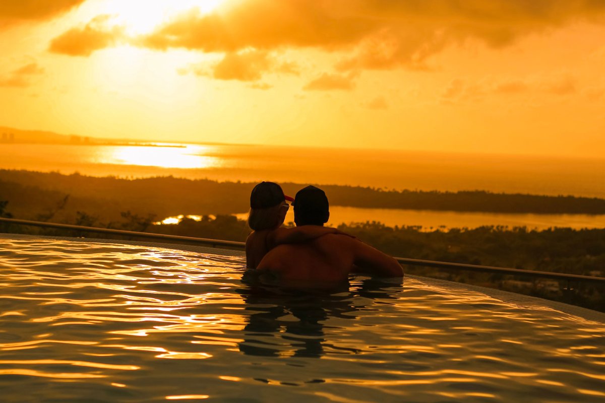 Una pareja contempla una puesta de sol desde una piscina infinita en Puerto Rico.