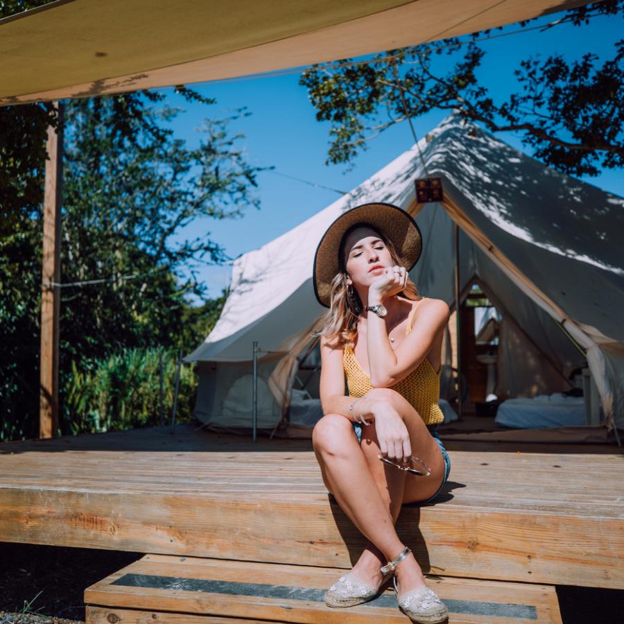 A girl sits in front of a camping tent at Pitahaya Glamping.